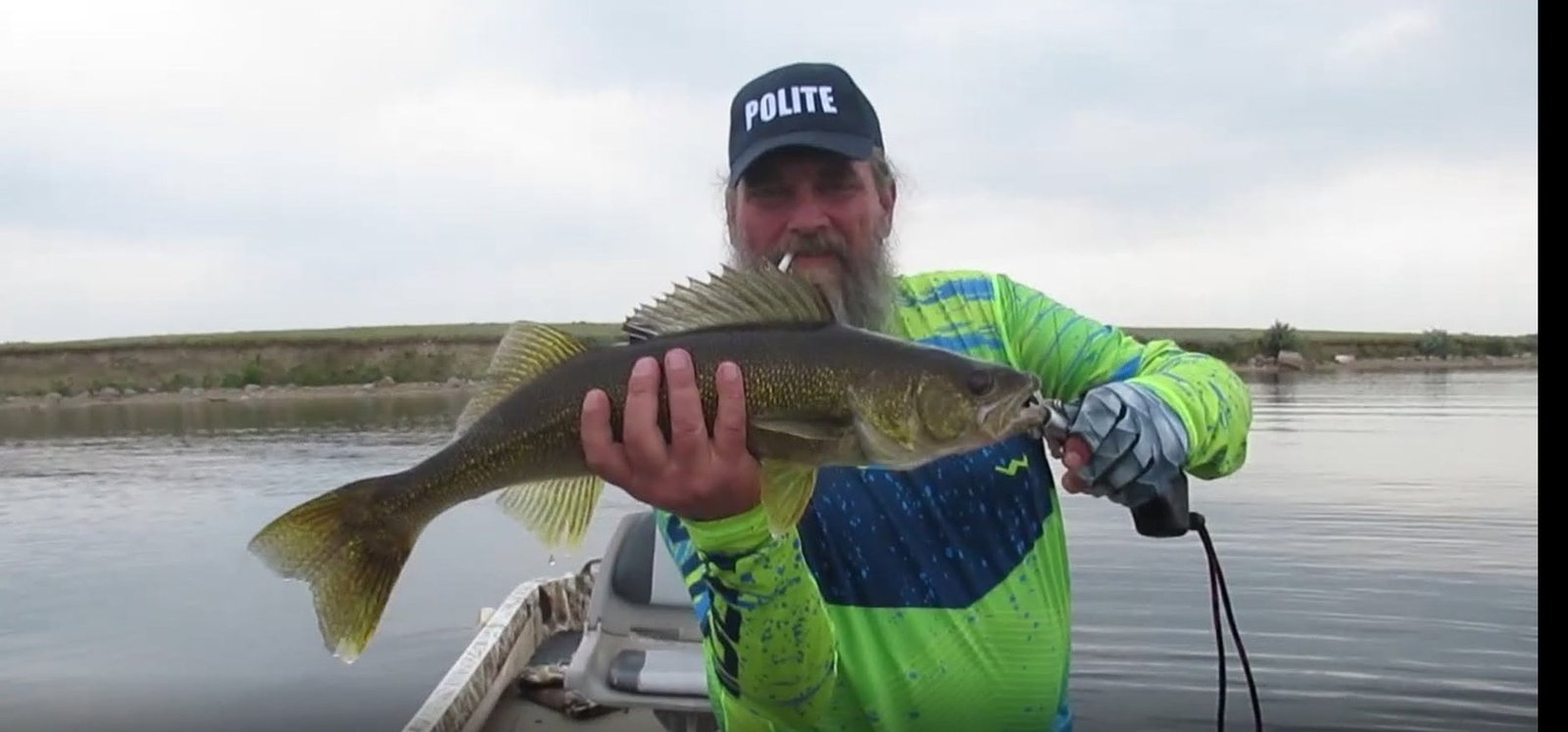 Kelly holding a walleye from the boat on calm water